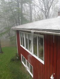 heavy rain is pouring over a gutter of a residential home