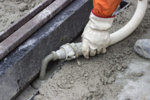 Worker applying grout to fill a void under a foundation