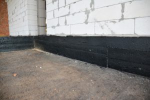 Building house construction with waterproofing spray-on tar.